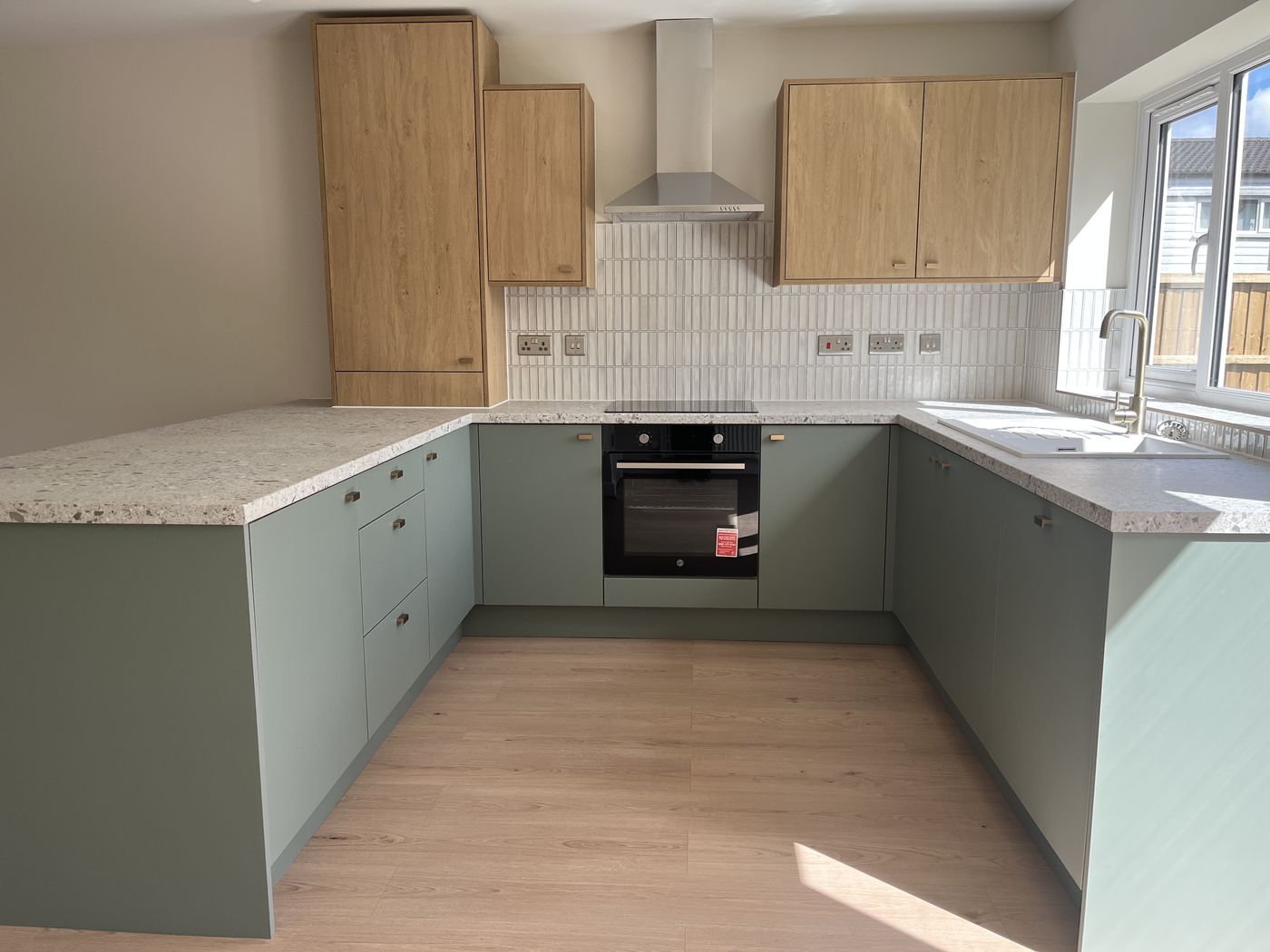Two-tone green and oak kitchen with terrazzo worktops at Sorrel Way